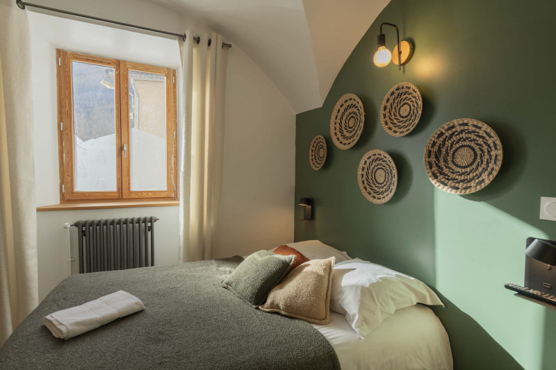Chambre d'hôtel bien décorée avec grand lit et fenêtre sur l'extérieur et vue montagne