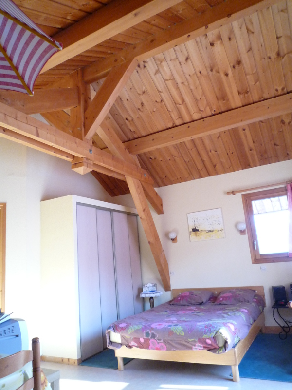 lit double dans le salon avec plafond en bois à chantemerle